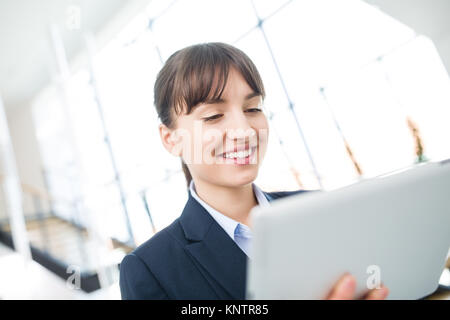 Young businesswoman smiling while using digital tablet in office Stock Photo
