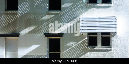 Angled shadows on a white stucco house making diagonal patterns with square doors and windows Stock Photo