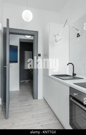 Kitchen with whitewashed wooden floor and gray door to hallway Stock Photo