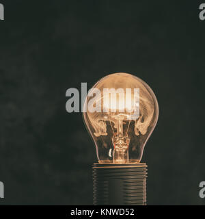 Square photo of the glass bulb mounted into the plastic socket. The bulb is full of hot particles, smoke and fumes from the wire which is burning with Stock Photo