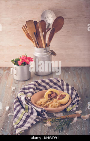 Vertical retro photo with vintage plate with portion of potato dumplings filled by smoked pork meat together with sour cabbage and fried onion. Kitche Stock Photo