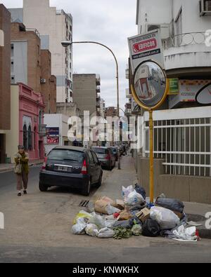 Cordoba, Argentina - 2016: A woman looks at a pile of garbage deposited on a street corner near the city center during a garbage collectors strike. Stock Photo