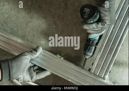 Man assembles profile metal frame for plasterboard ceilings Stock Photo