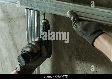 Man assembles profile metal frame for plasterboard ceilings Stock Photo