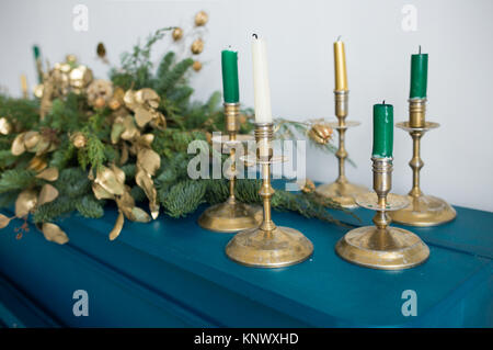 Closeup of candles and blurry Christmas garland  on wooden painted blue background of old piano decorated for holiday celebration. Golden elements of  Stock Photo