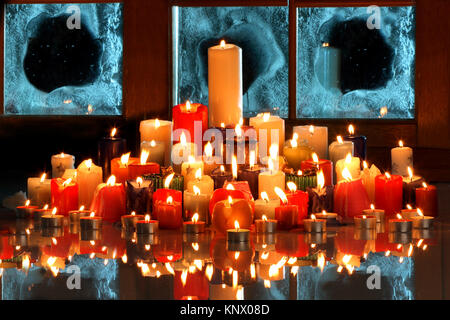 many burning candles in front of an iced window Stock Photo