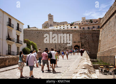 People walk toward 'Portal de ses Taules'  that is massive arched gate through fortified walls to the steep, narrow streets of the old city. Catedral  Stock Photo