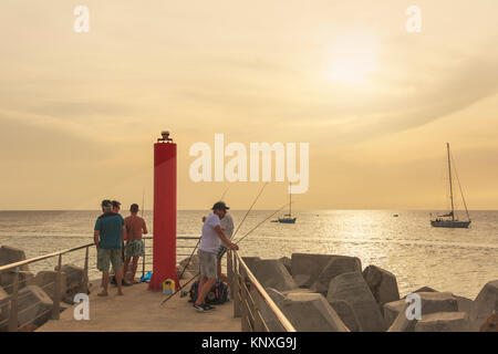 Fishermen at the end of the pier at Bikini Bay, Sal, Salinas, Cape Verde, Africa at sunset Stock Photo