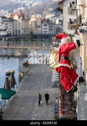 Lucerne, Switzerland - 3 Dec 2017: As Christmas decorations, a Santa Claus puppet with Christmas presents is climbing up the facade of a house at Luce Stock Photo