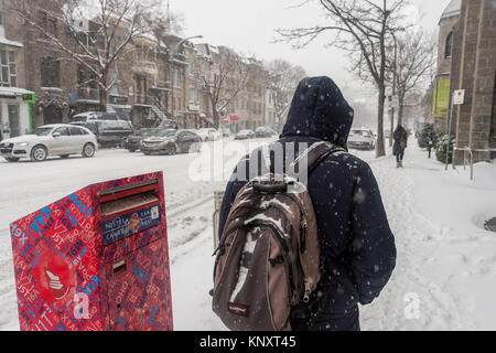 Montreal, Canada - 12 December 2017: Pedestrian walking on Saint Denis Street during first snow storm of the season. Stock Photo