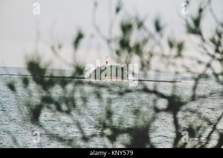 Sneak peek of a lighthouse across the ocean. Stock Photo