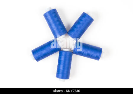 Five dark blue sewing threads laying in a circle on a white background, sewing accessories Stock Photo