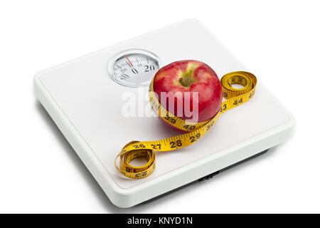 apple tied with tape measure on weight scale Stock Photo