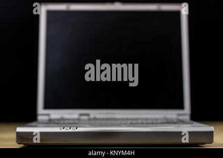 old laptop on a wooden table. Laptop with turned off monitor on a black background Stock Photo