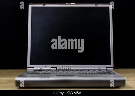 old laptop on a wooden table. Laptop with turned off monitor on a black background Stock Photo