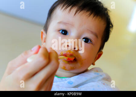 happy eating little asian boy enjoys eating food Stock Photo