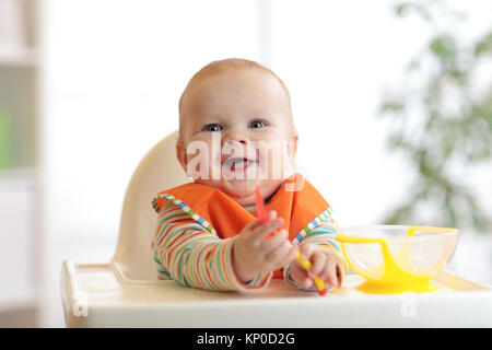 happy baby boy with spoon at table Stock Photo