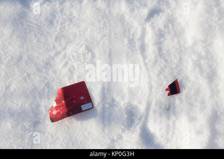 Red broken credit card lies on snow with footprint background Stock Photo