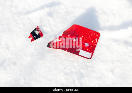 Red broken credit card lies on snow background Stock Photo