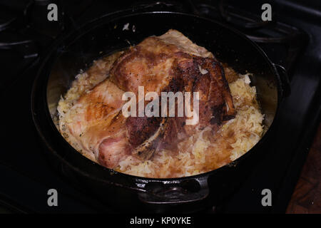 Pork rib end roast cooking with sauerkraut in an antique Griswold cast iron Dutch oven on a cold winter day in Speculator, NY Stock Photo