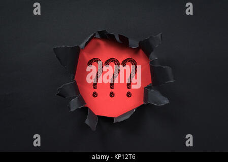 black torn paper revealing question mark on red paper. question mark background Stock Photo