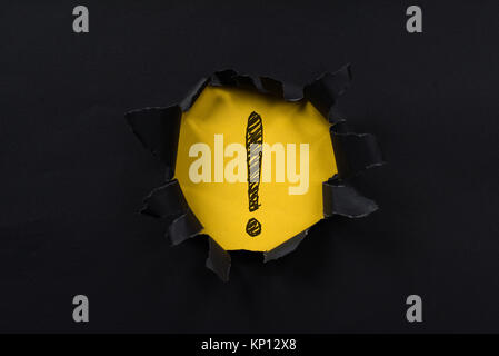 black torn paper revealing exclamation mark on yellow paper. exclamation mark background concept Stock Photo