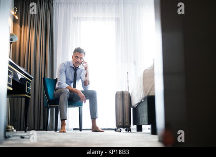 Mature businessman with smartphone in a hotel room. Stock Photo