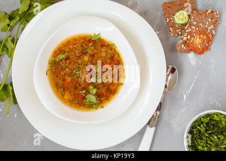 Peruvian quinoa soup, red rice and lentils in a white plate with herbs and crispbread. Healthy vegan food concept. Stock Photo