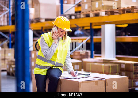 Woman warehouse worker with smartphone. Stock Photo