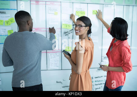 Executives preparing sticky notes on whiteboard in office Stock Photo