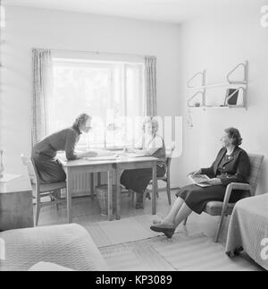 Two female students at boarding school in a dormitory room with adult woman housemistress teacher, Helsinki, Finland, 1950s Stock Photo