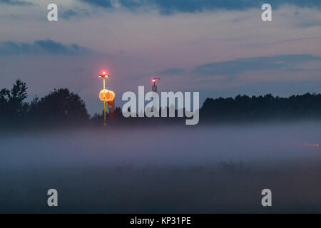 Empty runway at airport during a foggy evening. Illuminated runway on a foggy evening. Foggy runway. Blured. Stock Photo