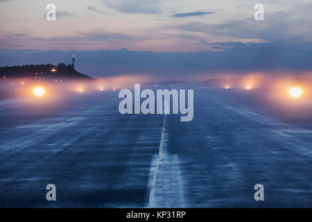 Empty runway at airport during a foggy evening. Illuminated runway on a foggy evening. Foggy runway. Blured. Stock Photo