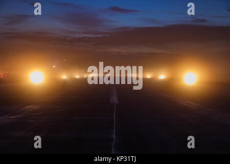 Empty runway at airport during a foggy evening. Illuminated runway on a foggy evening. Foggy runway. Blured. Stock Photo