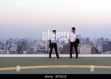 Fist Bumping Corporate Colleagues Teamwork between professional Couple businessman over the cityscape background at evening time, Business success con Stock Photo