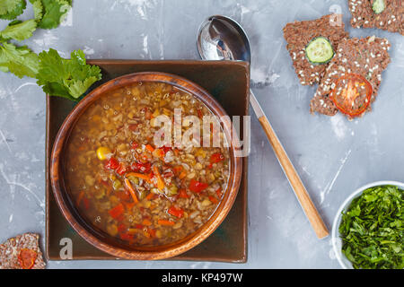 Peruvian soup with quinoa, red rice and lentils in a wooden bowl with herbs and healthy crispbread. Healthy vegan food concept. Stock Photo