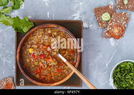 Peruvian soup with quinoa, red rice and lentils in a wooden bowl with herbs and healthy crispbread. Healthy vegan food concept. Stock Photo