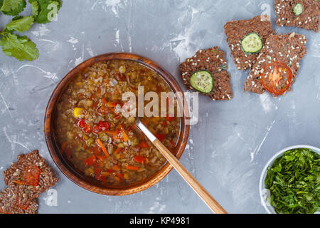 Peruvian soup with quinoa, red rice and lentils in a wooden bowl with herbs and healthy crispbread. Healthy vegan food concept. Stock Photo