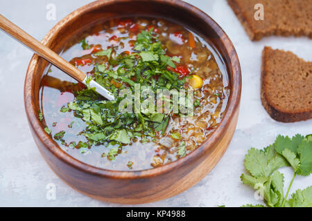 Peruvian soup with quinoa, red rice and lentils in a wooden bowl with herbs and rye bread. Healthy vegan food concept. Stock Photo