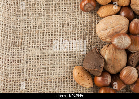 Whole unshelled hazelnuts, walnuts, amonds and brazilnuts  on burlap sack with copy space Stock Photo