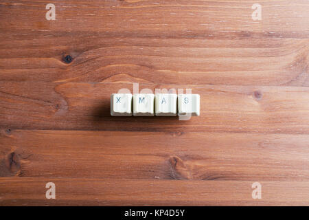 Xmas word. Flat lay view from above on the table with computer keyboard keys buttons on a wooden background. Xmas concept. Stock Photo