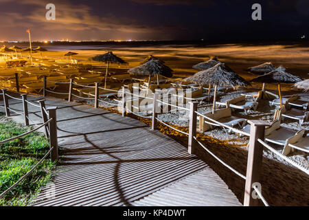Beach at night. Wooden path to the beach, view at night on a beautiful beach by the sea. Evening romance by the sea. Stock Photo