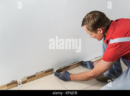 Laying the tiles. Tiler  installs the border of tiles Stock Photo