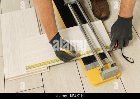 Laying Ceramic Tiles. Worker measures the ceramic tiles for further cutting Stock Photo