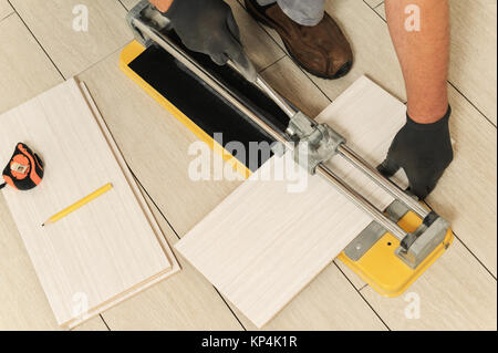 Laying Ceramic Tiles. Tiler cuts tile  manual cutter Stock Photo