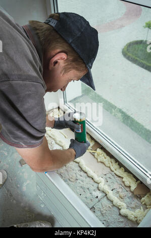 The worker installs a plastic sill using polyurethane foam Stock Photo