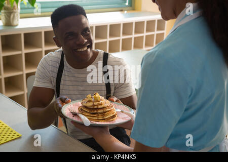 Waitress serving breakfast to man in restaurant Stock Photo