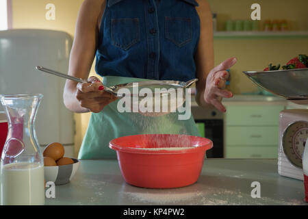 Woman using strainer in kitchen at home Stock Photo