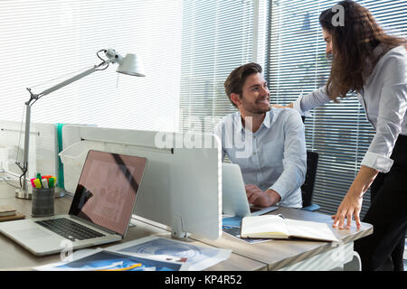 Male and female executives discussing over laptop in office Stock Photo
