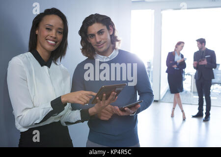 Male and female executives discussing over digital tablet in office Stock Photo